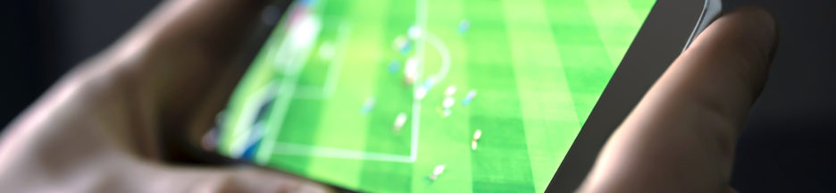 Watching football and sport stream with mobile phone. Man streaming soccer game live, video replay or highlights online with smart device. Ligue 1, Free lance une application pour suivre des matchs de football