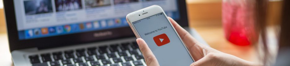 Regarder-en-accéléré Une femme tenant un smartphone et qui visionne YouTube sur PC