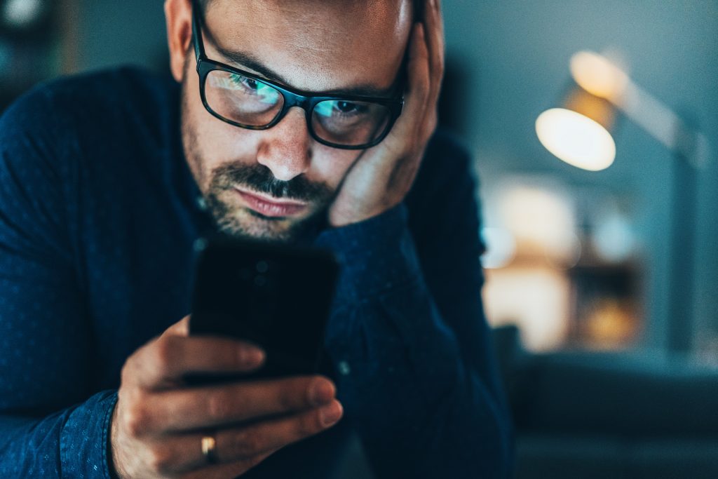 Un homme fixant l’écran de son smartphone