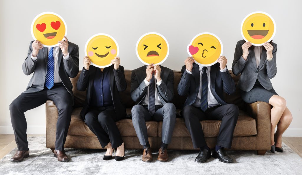 Cinq personnes sur un canapé, les visages couverts par des emojis