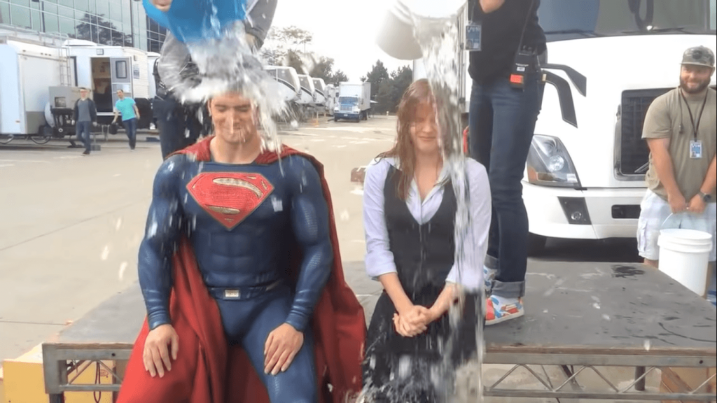 Homme déguisé en superman et femme recevant des seau d’eau sur la tête