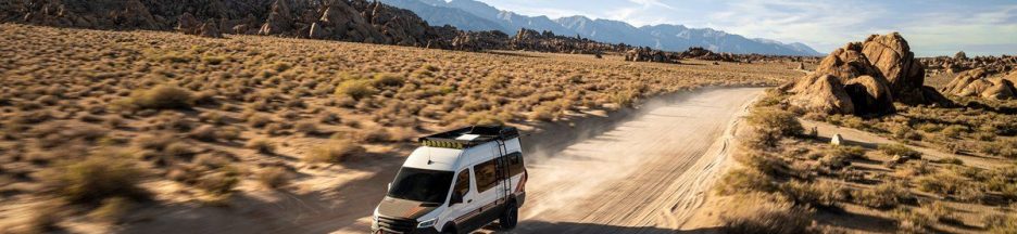internet-par-satellite-kit- voiture-mobile Un van fonçant sur une route non goudronnée, avec un décor de canyon en arrière-plan et au beau milieu de nulle part.