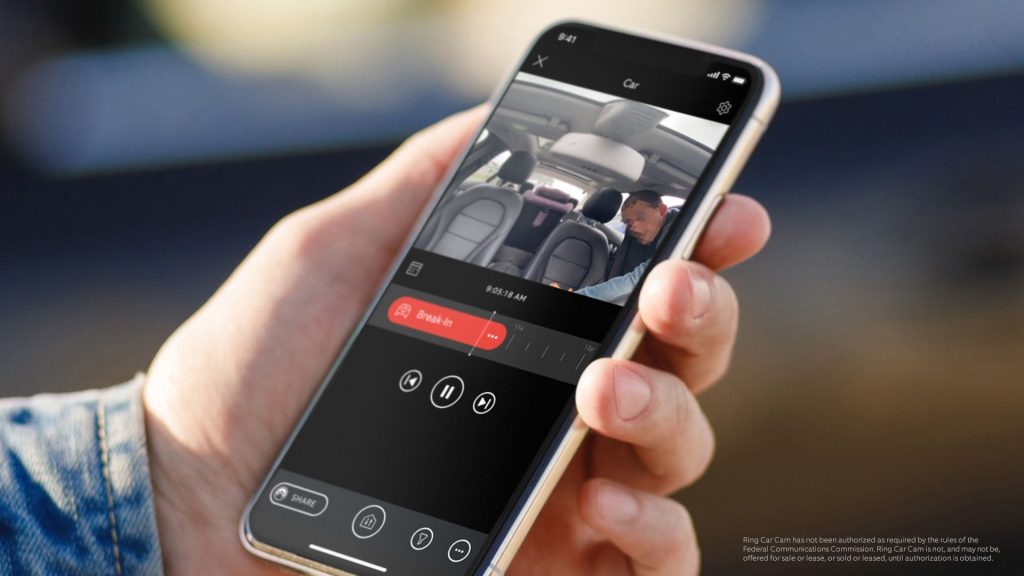 Une main qui tient un smartphone affichant une application de suivi d’enregistrement vidéo dans une voiture.