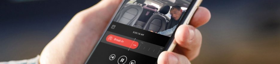 ring-alarme-connectee-auto Une main qui tient un smartphone affichant une application de suivi d’enregistrement vidéo dans une voiture.