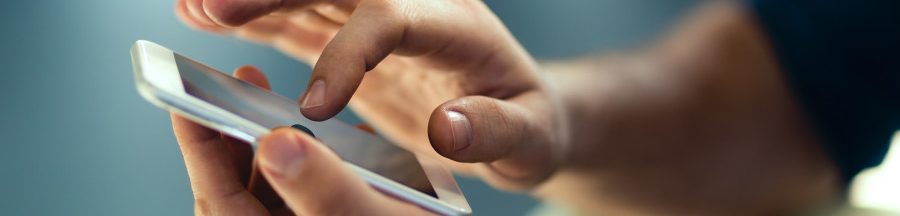 controle-parental-smartphone-decret Un adulte en train de manipuler un petit smartphone dans le cadre d’un contrôle parental.