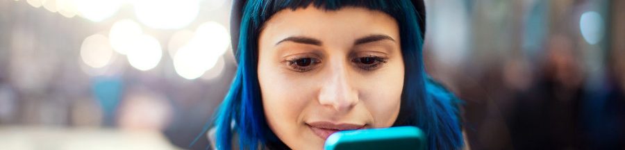 Une jeune femme en train de composer un SMS sur son smartphone.