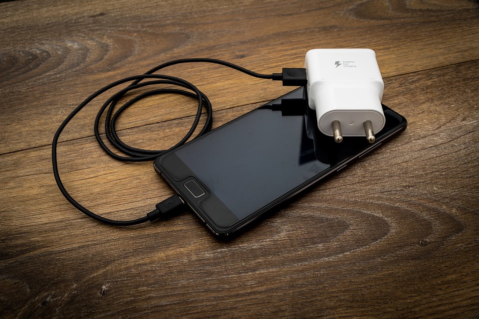 Un smartphone avec son chargeur qui aurait bien besoin d’une solution d’alimentation back up en cas de coupure d’électricité.