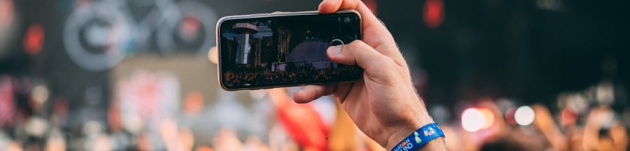 Un homme avec le smartphone levé prenant la vidéo d’un évènement issu de l’industrie du live