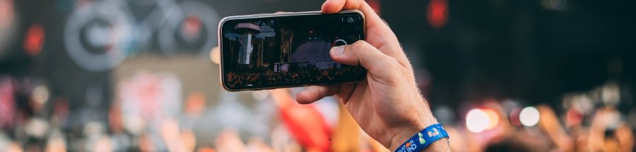 smartphone-industrie-du-live Un homme avec le smartphone levé prenant la vidéo d’un évènement issu de l’industrie du live