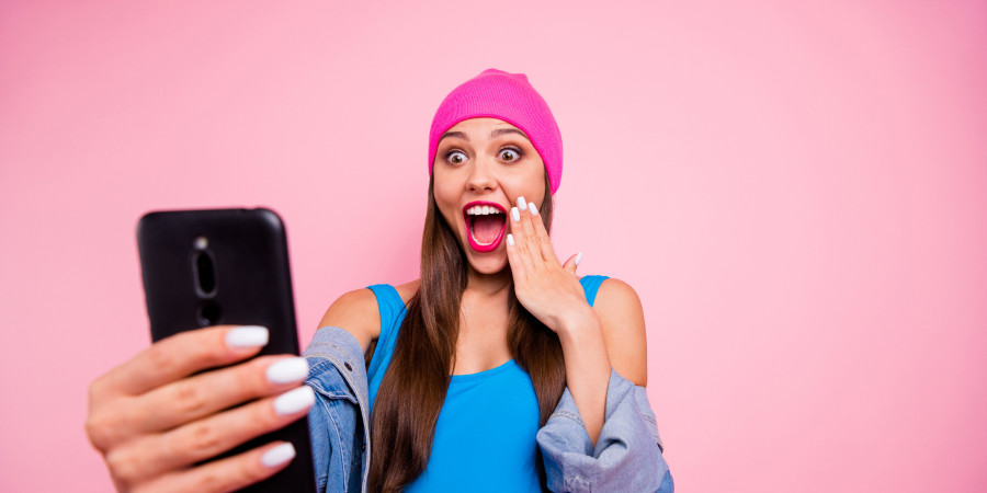 Une utilisatrice de TikTok, smartphone à la main, s’excitant d’une publication avec le hashtag « Mascara wand »