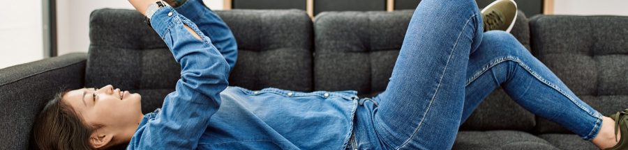 format-notes-reseaux-sociaux-instagram-twitter Une jeune femme allongée sur un sofa et en train de lire des textes de formats Notes sur les réseaux sociaux.