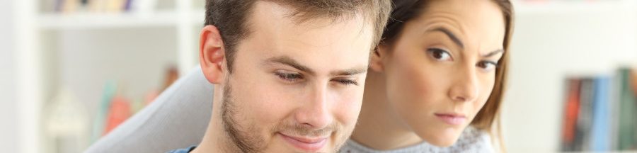snooping-espionner-smartphone-conjoint Une femme en plein snooping, épiant le smartphone de son conjoint par-dessus son épaule.
