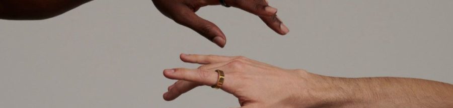 Deux mains tendues l’une vers l’autre, portant chacune une bague connectée au doigt.