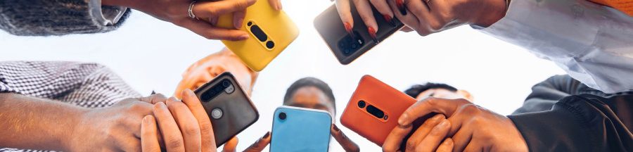 smartphone-pour-ado-choisir-criteres-rentree-scolaire Des jeunes debout en cercle, tenant dans leurs mains un smartphone pour ado.