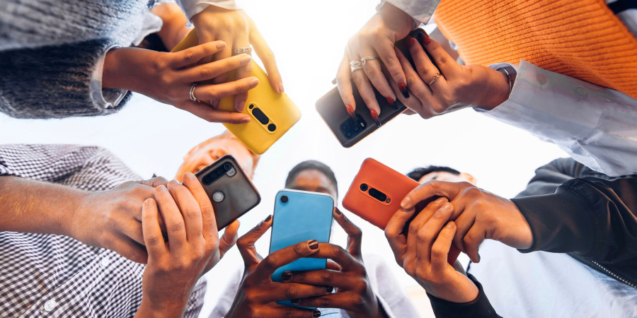 Des jeunes debout en cercle, tenant dans leurs mains un smartphone pour ado.