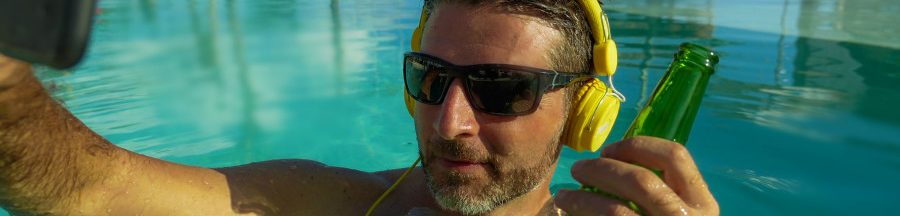 Un homme se relaxant dans une piscine, exposant son téléphone au soleil et ignorant les gestes pour éviter une surchauffe de smartphone.