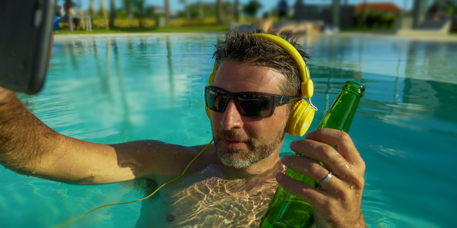 Un homme se relaxant dans une piscine, exposant son téléphone au soleil et ignorant les gestes pour éviter une surchauffe de smartphone.