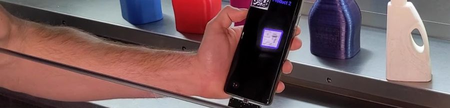 Un smartphone identifiant le QR Code invisible d’une petite bouteille faite en impression 3D.