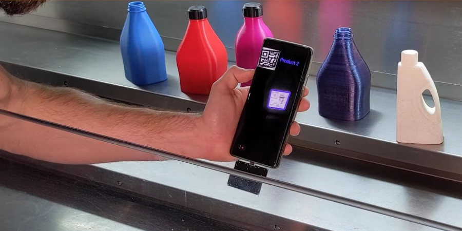 Un smartphone identifiant le QR Code invisible d’une petite bouteille faite en impression 3D.