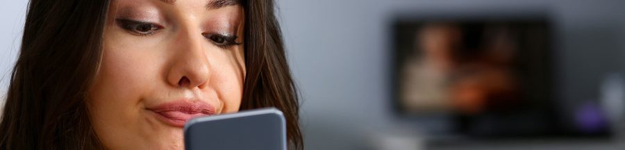 Une femme regardant son smartphone Android, faisant le constat d’un avertissement de restriction de capture d’écran.