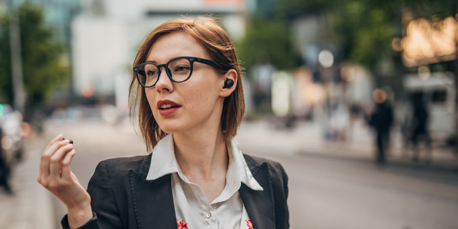 Une femme dans la rue utilisant les Pixels Buds de Google, qui compte lancer une fonction de protection auditive sur Android 14.