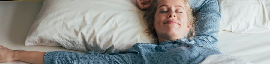 Une femme dans son lit, profitant des quelques minutes de répit accordées par la répétition d’alarme de la fonction snooze de son réveil.