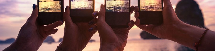 prendre-des-photos-sur-smartphone-fonction-preferee-francais Des vacanciers au bord de la plage en train de prendre des photos sur smartphone.
