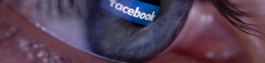 Un millénial avec le logo de FB se reflétant dans ses yeux, un fervent utilisateur du réseau social fêtant cette année 2024 les 20 ans de Facebook.