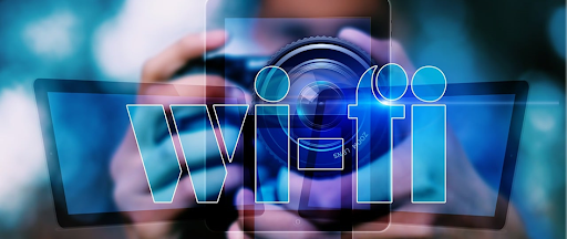 Le mot Wi-fi affiché en gros plan avec une personne tenant des appareils numériques en arrière-plan. Le mot Wi-fi affiché en gros plan avec une personne tenant des appareils numériques en arrière-plan.