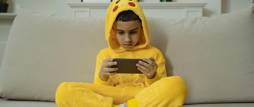 Un enfant assis jouant sur son téléphone.