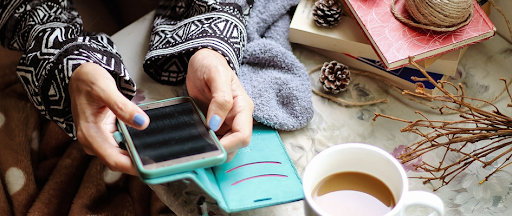 Une femme habillée chaudement, assise à une table et tenant son smartphone dans les mains. Une femme habillée chaudement, assise à une table et tenant son smartphone dans les mains.