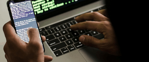 Un developpeur d’applications mobiles travaillant des codes de programmation sur son PC et son smartphone.