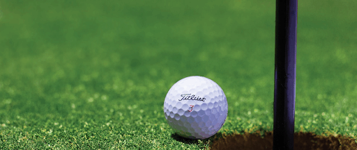 Une balle de golf sur green, à deux doigts de tomber dans un trou. Une balle de golf sur green, à deux doigts de tomber dans un trou.