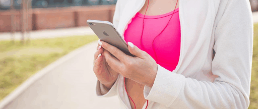 Une femme en tenue de sport, écouteurs aux oreilles et smartphone à la main. Une femme en tenue de sport, écouteurs aux oreilles et smartphone à la main.