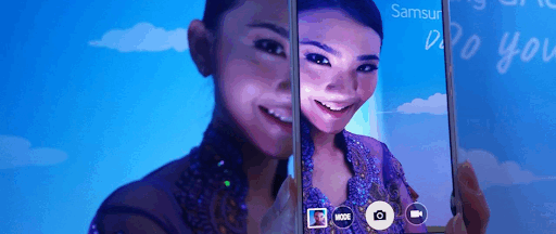 Une femme tenant un smartphone Samsung à un évènement de la marque high-tech.