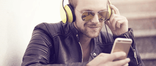 Un homme en train d’écouter de la musique via son smartphone et un casque audio. Un homme en train d’écouter de la musique via son smartphone et un casque audio.