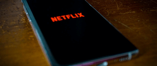 Un smartphone posé sur une table en bois, avec l’application Netflix en cours d’exécution. Un smartphone posé sur une table en bois, avec l’application Netflix en cours d’exécution.
