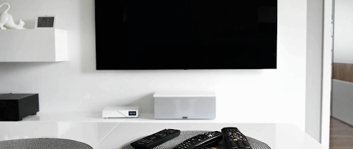 Un téléviseur accroché au mur d’un salon d’un blanc immaculé.