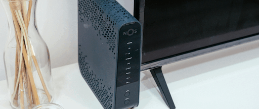 Une box internet de couleur noire posée à côté d’un téléviseur.