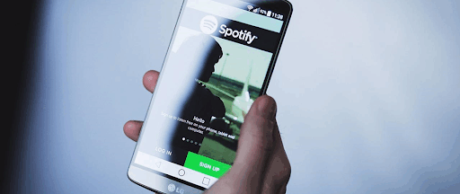 Une main tenant un smartphone avec l’application Spotify ouverte. Une main tenant un smartphone avec l’application Spotify ouverte.