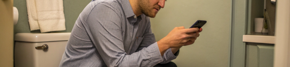 un homme qui utilise son téléphone aux toilettes