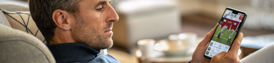 un homme qui suit l'actu sport sur son smartphone