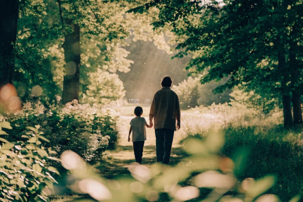 Parent et enfant marchant main dans la main dans un parc ensoleillé