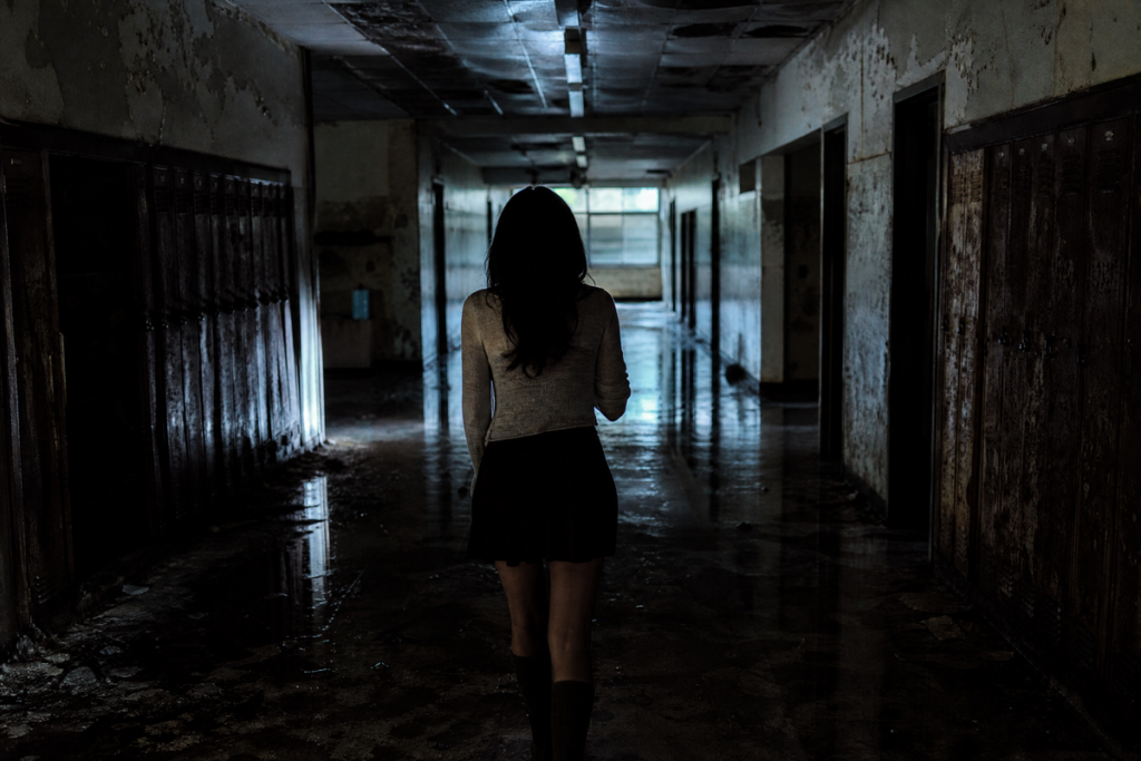 Jeune femme marchant dans le couloir d'un lycée abandonné