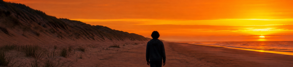 Un adolescent vu de dos marchant seul sur une plage