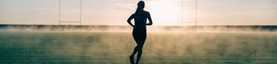 Silhouette de joueuse de football s'échauffant seule sur un terrain vide
