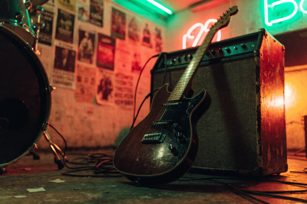 Guitare électrique posée contre un ampli dans un garage éclairé au néon