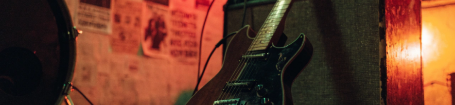 Guitare électrique posée contre un ampli dans un garage éclairé au néon