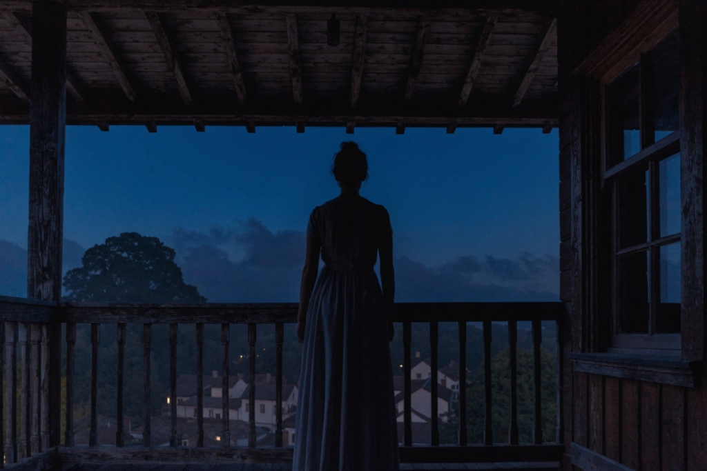 Silhouette d'une femme âgée regardant au loin depuis un balcon colonial