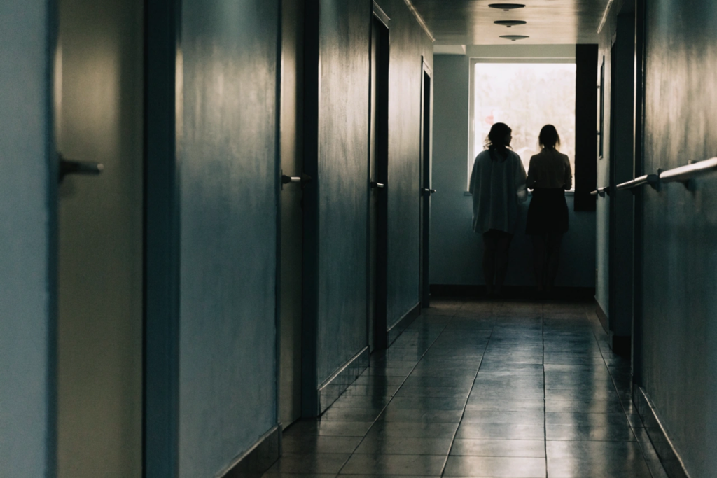 Deux silhouettes de femmes à une fenêtre lumineuse d'un couloir